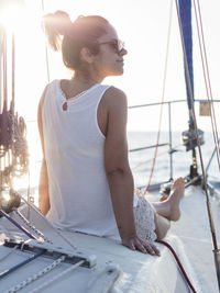 Rear view of woman looking away while sitting in sailboat against clear sky