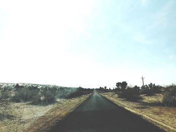 Road amidst trees against clear sky
