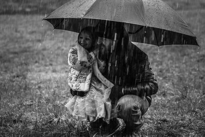 Full length of happy woman holding umbrella on field