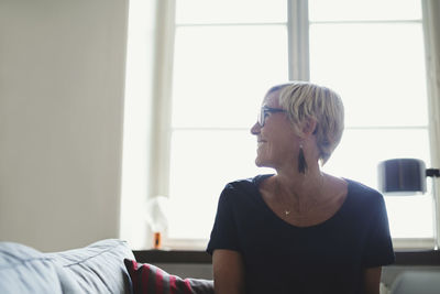 Happy designer looking away while sitting on sofa at home