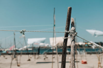 Close-up of wooden clothesline at beach against sky