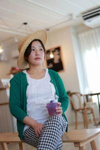 A pregnant woman in a white-green blouse is relaxed in a modern house drinking juice. 