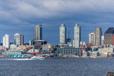 A water taxi cruises across elliott bay in front of the seattle skyline.