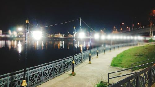 Illuminated bridge over river against sky at night