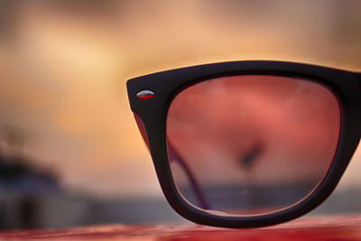 Close-up of sunglasses on mirror against sky