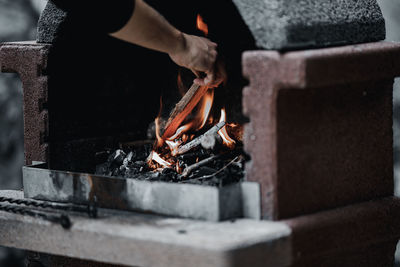 Cropped hands putting wood in fireplace