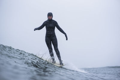 Full length of man standing in sea against sky during winter