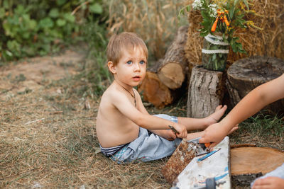 High angle view of shirtless boy sitting on land