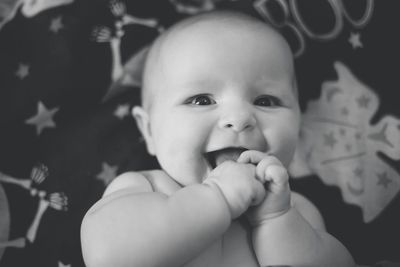 Close-up portrait of cute baby girl lying down on bed at home