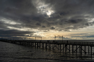 Pier over sea against sky during sunset