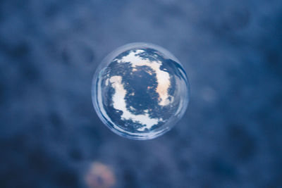 Close-up of crystal ball against blue sky