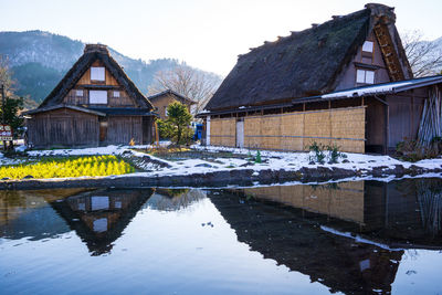 Houses by lake against buildings during winter