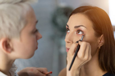 Beautician applying make-up to fashion model in studio