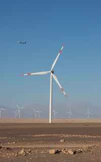 Wind turbines on field against sky