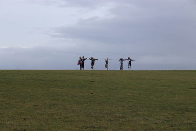 People standing on field against sky