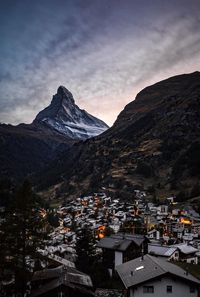 Aerial view of townscape by mountains against sky