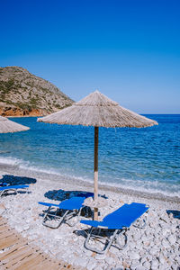 Deck chairs on beach against clear blue sky