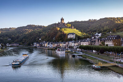 Scenic view of river by buildings against clear sky