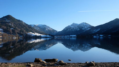 Scenic view of lake by mountains against clear blue sky