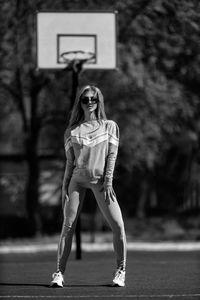 Portrait of young woman standing against trees