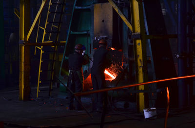 People standing by fire at night