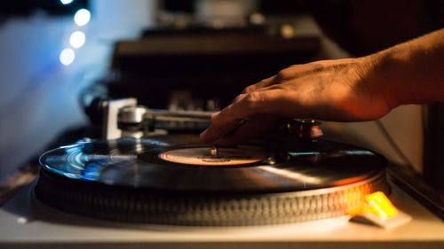 Cropped hand touching record playing on turntable