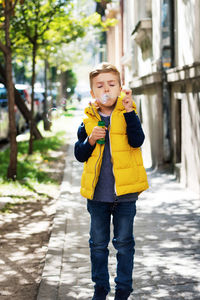 Cute kid kid blowing soap bubbles while walking on the street.