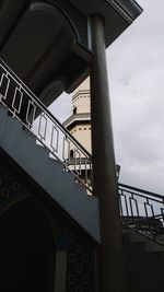 Low angle view of bridge by building against sky