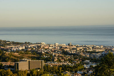 High angle view of cityscape by sea against clear sky