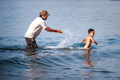 Full length of siblings playing in sea