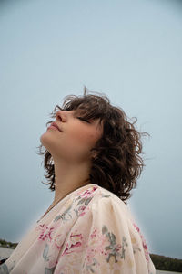 Side view of woman looking away against sky