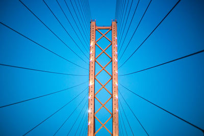 Low angle view of suspension bridge against blue sky