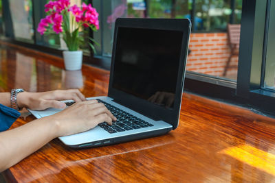 Cropped hands using laptop on table