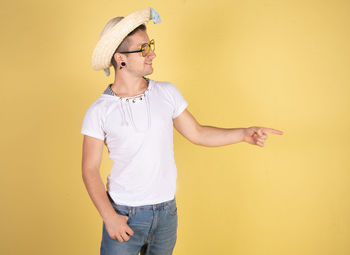 Full length of young man standing against yellow wall