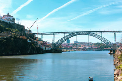 Bridge over river in city against sky
