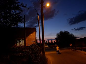 Street by building against sky at sunset