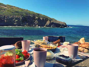 Table by sea and mountains against sky