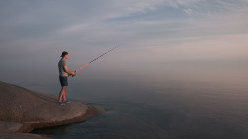 Fisherman with a fishing rod on the shore of a calm sea. get away from society and relax