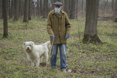 Full length of man with dog standing in forest
