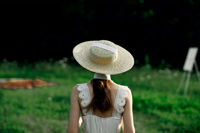 Rear view of woman wearing hat standing on field