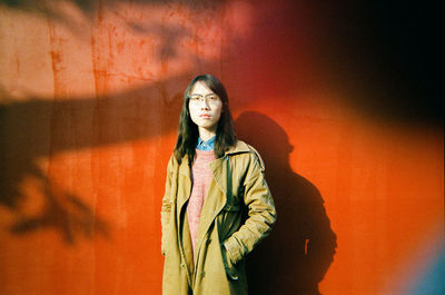 Portrait of young woman standing against wall outdoors