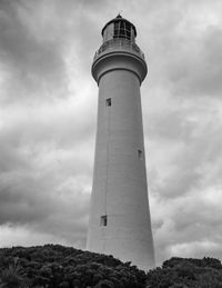 Low angle view of lighthouse by building against sky