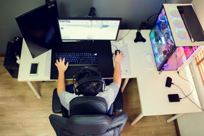 Rear view of man using mobile phone while sitting on table