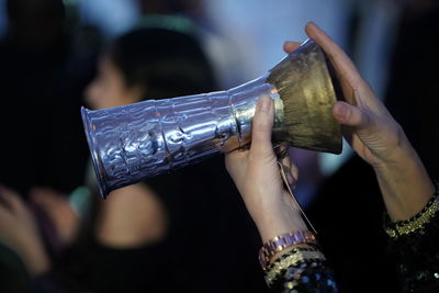 Close-up of woman holding bottle against blurred background
