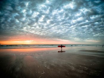 Scenic view of beach against cloudy sky