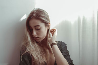 Close-up of young woman looking down against wall