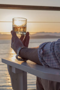 Man holding glass of beer at sunset