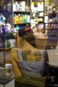 Rear view of woman sitting on chair in cafe