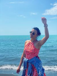 Portrait of woman standing at beach against sky