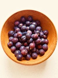 Heaped plums in grained wooden bowl. purplish blue. foraged in community orchard. fresh and juicy.